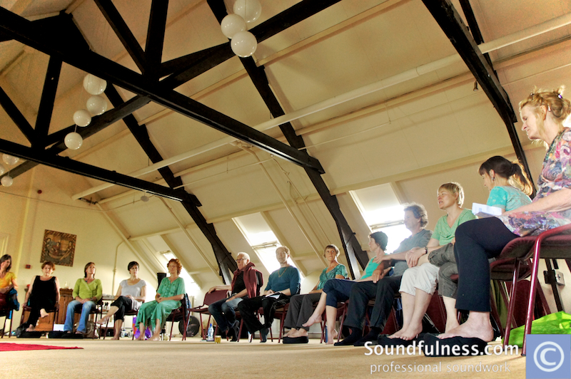 Large seated circle of participants under an attic beam ceiling with paper lanterns