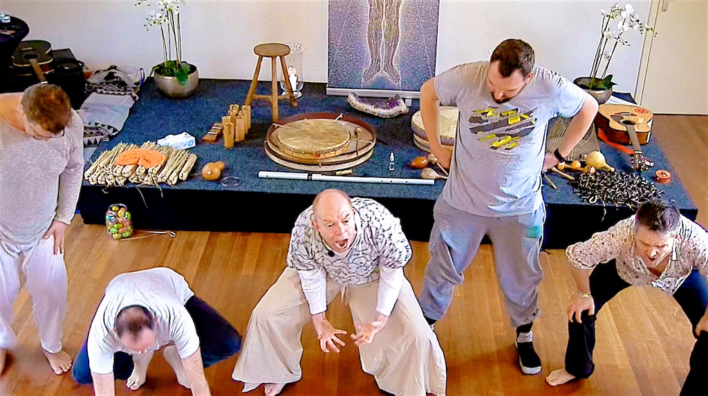 Group of men in low warrior stance led by Coen in front of the instrument stage