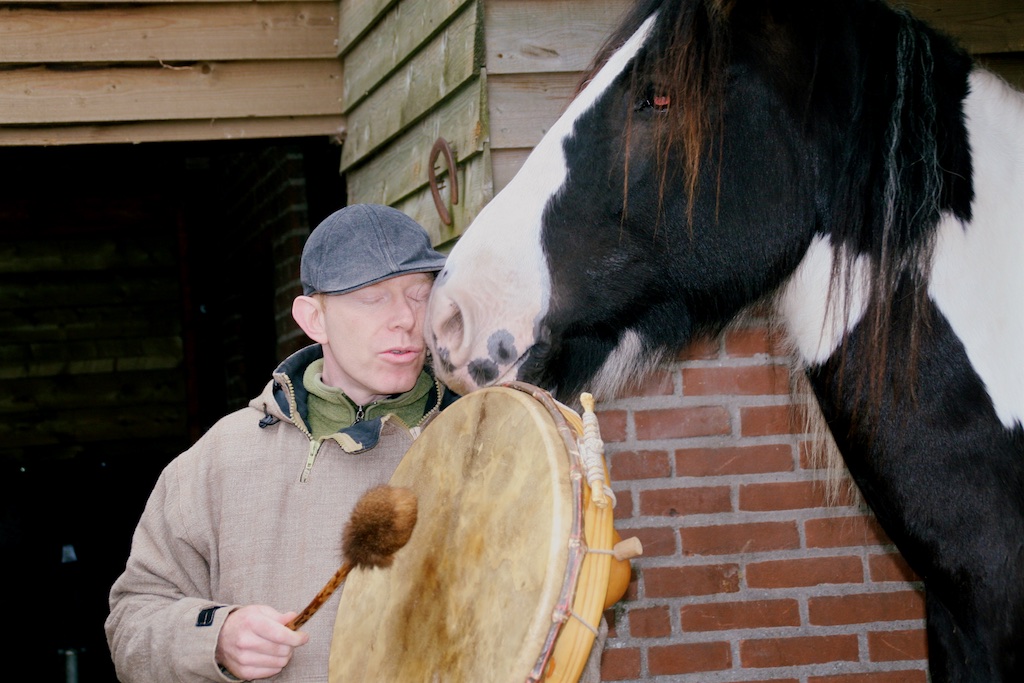 Coen playing a frame drum with a horse