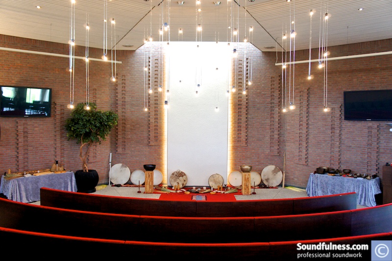 Corporate amphitheatre set with a row of frame drums and pendant lights above