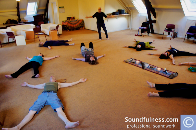Participants lying star-shaped on the floor while Coen guides from the centre