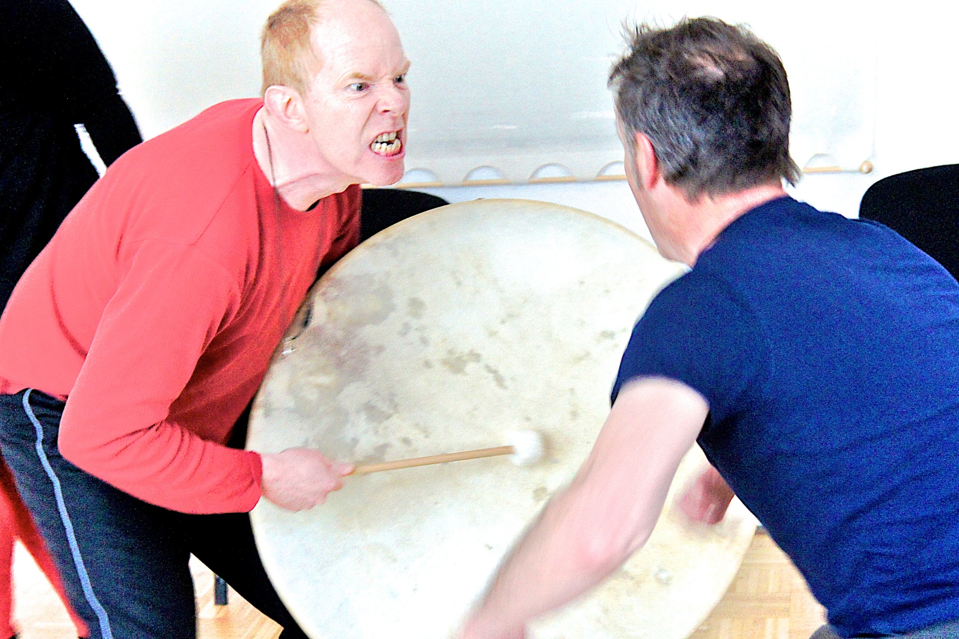 Two participants drumming face to face with intensity