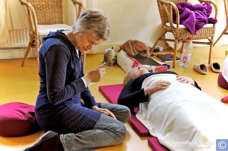 Practitioner brushing a feather rattle across a resting participant's face