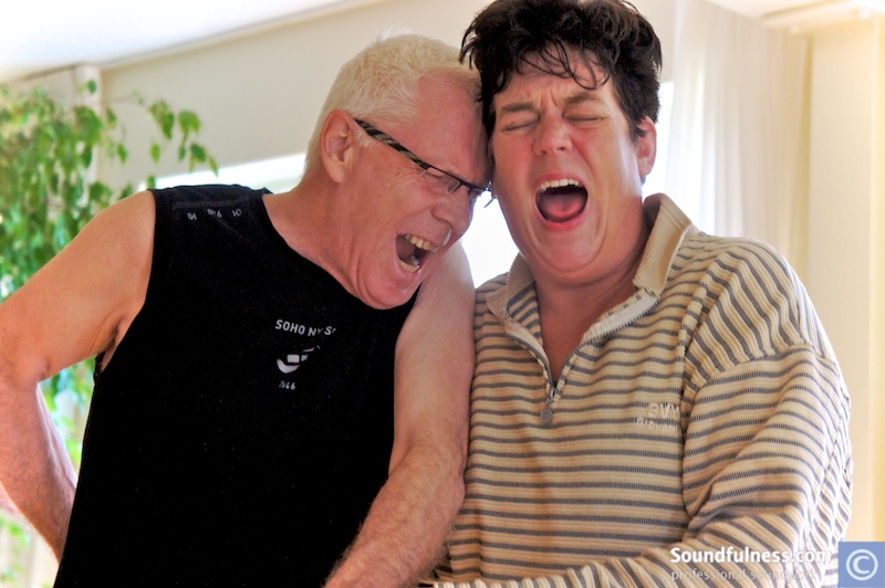 Two participants forehead-to-forehead in full laughter during a session