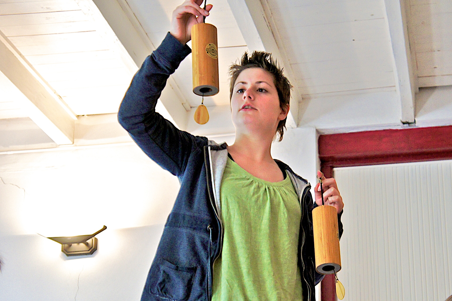 Practitioner demonstrating a pair of Koshi chimes in a light-filled studio