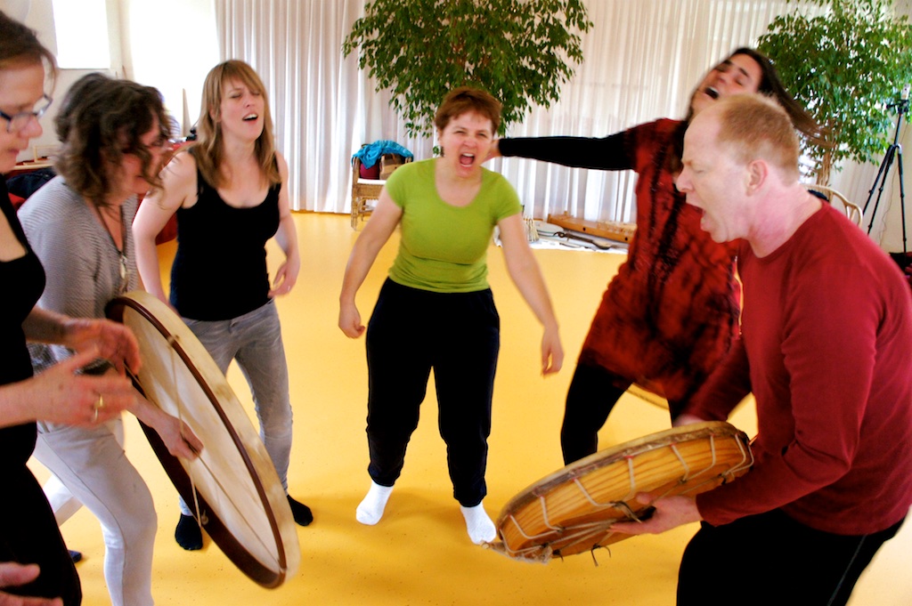 Coen and participants drumming and singing with wide open mouths in joy