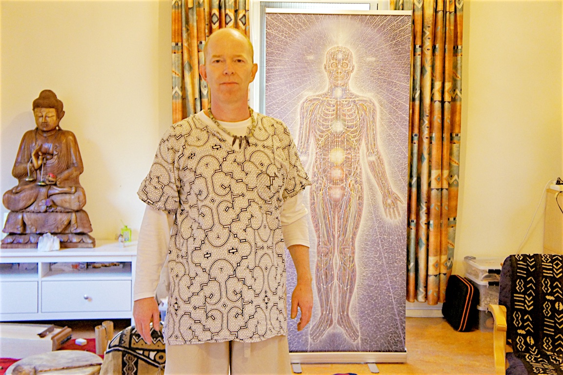 Coen standing beside a life-size meridian and chakra banner in his practice room