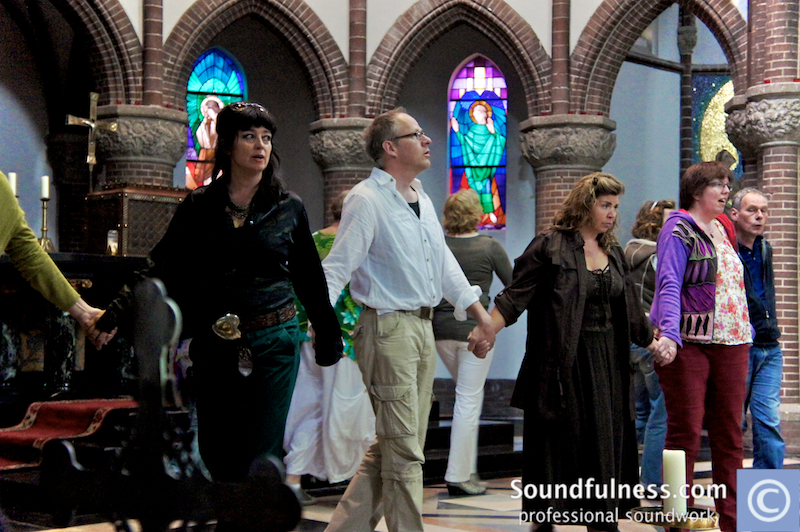 Participants holding hands in a circle inside a stained-glass church