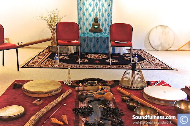 Sound ritual room with two red chairs, Buddha altar and instruments laid out on a red cloth