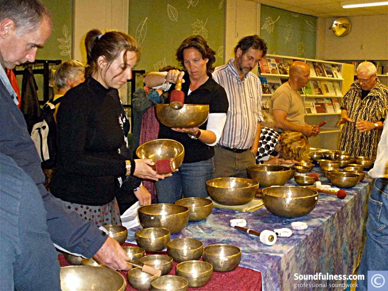 Visitors testing singing bowls at a hands-on Soundfulness fair table