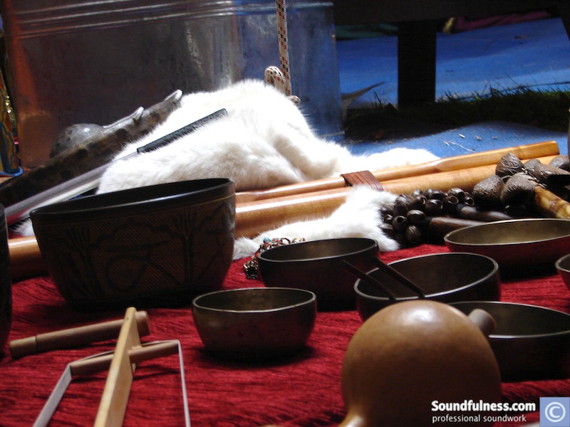 Still life of singing bowls, seed pods and a white pelt on red cloth