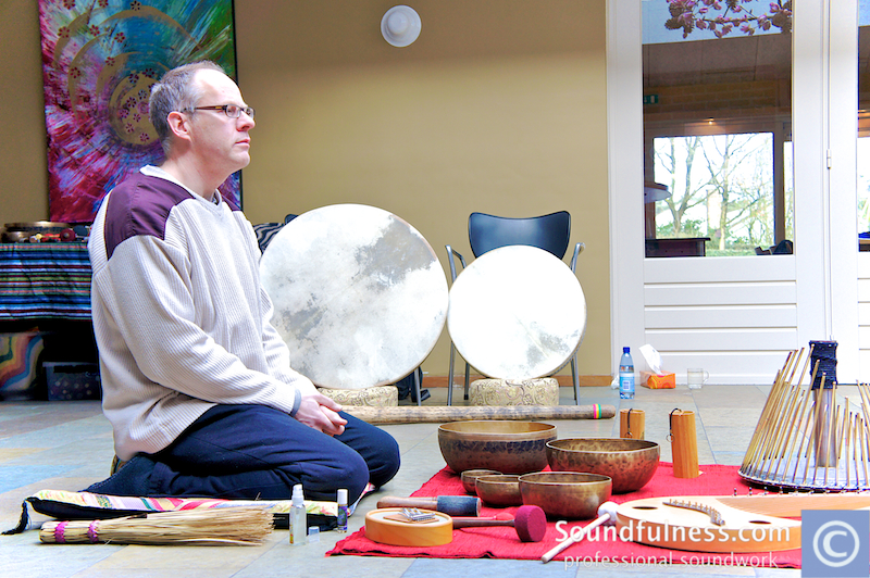 Coen seated in meditation with two large frame drums and instruments during a year training