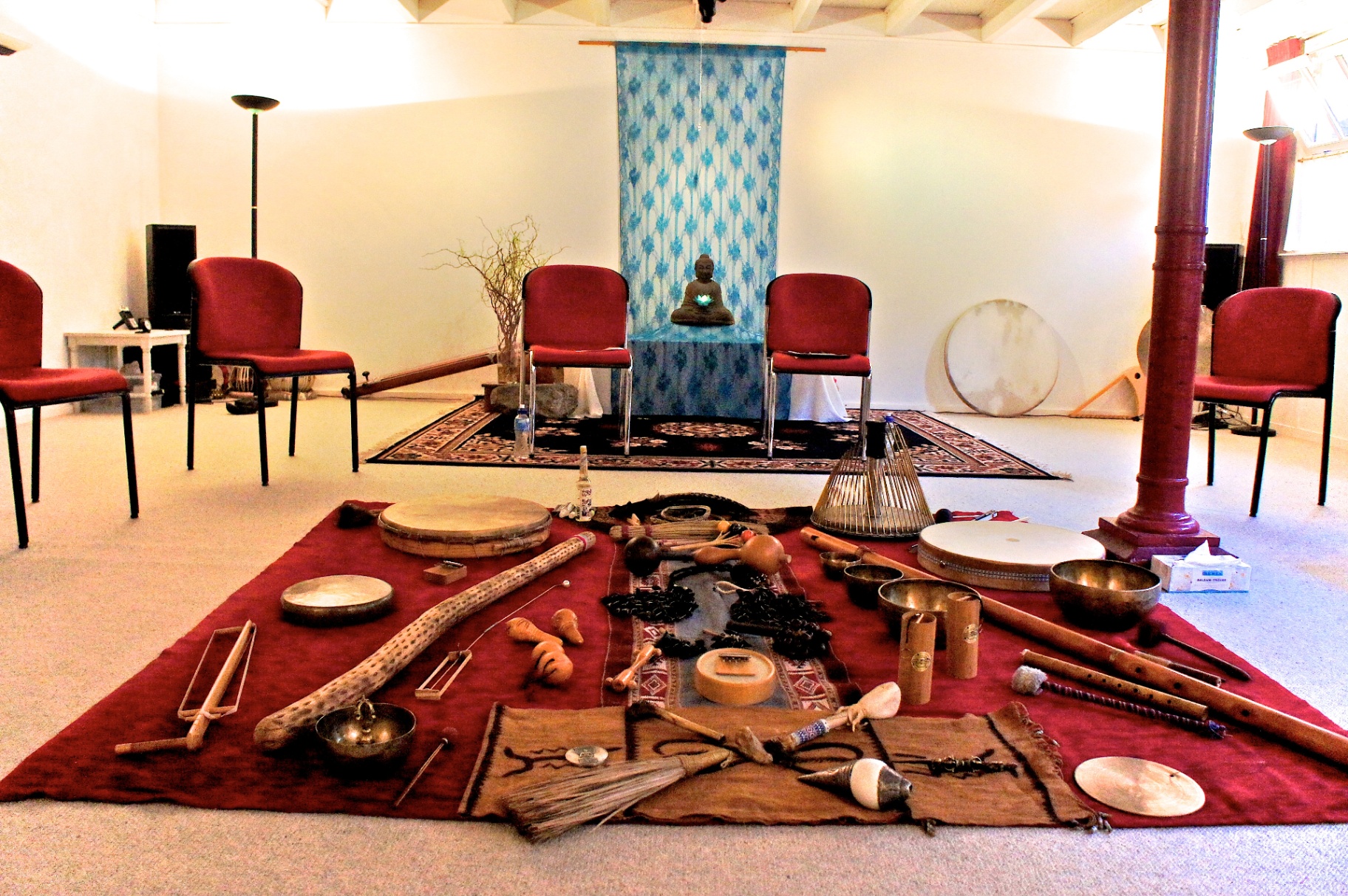 Full instrument set laid out on a red rug with chairs and Buddha altar in the background