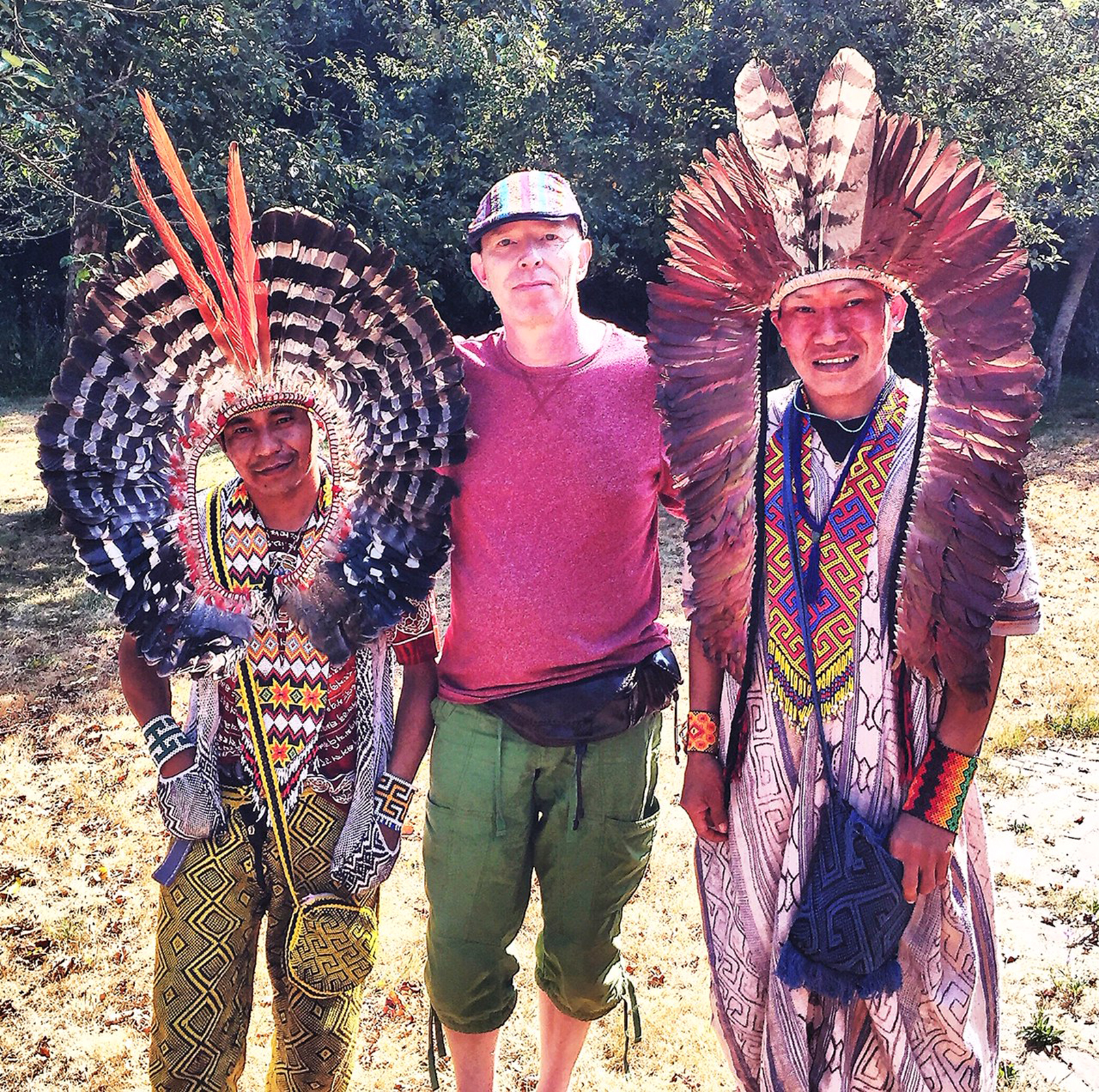 Coen with two indigenous elders in traditional feather headdresses