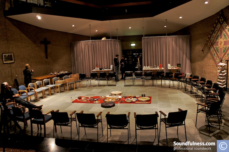 Empty parish hall set with a wide circle of chairs and instrument altar in the center
