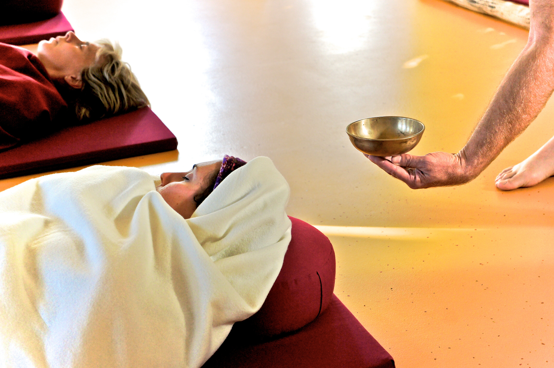 Participants resting under blankets as Coen offers a Tibetan singing bowl