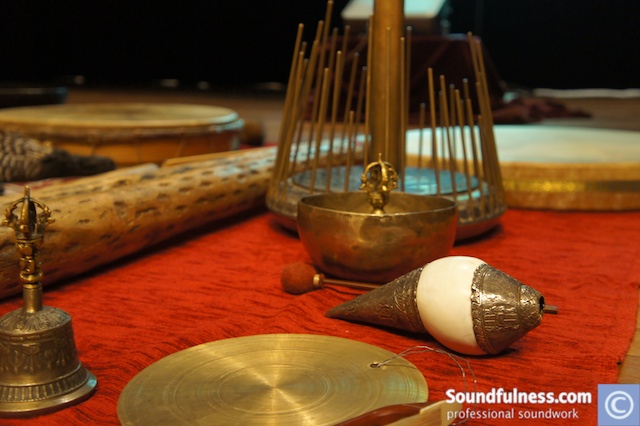 Close-up of ritual altar with bell, gong, singing bowl and shanti chime on red cloth
