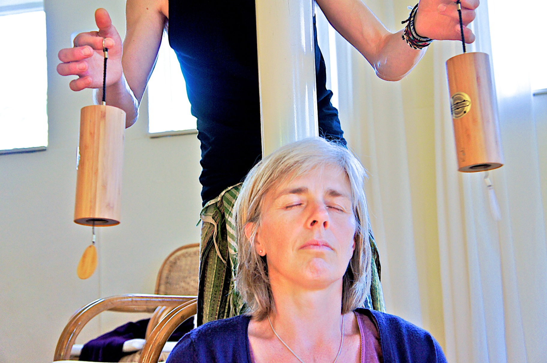 Two Koshi chimes played above a seated woman's head with closed eyes