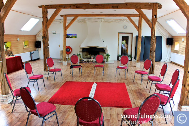 Barn loft with wooden beams, red chairs in a circle and red carpet centrepiece