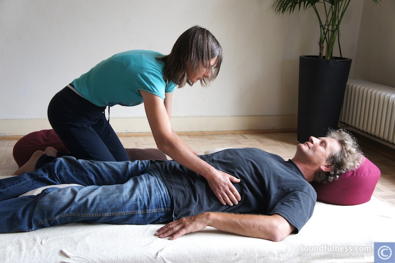 Practitioner placing hands on a resting client during a floor session
