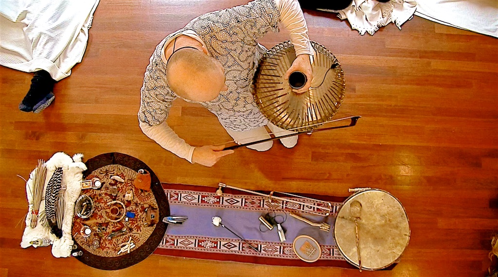 Overhead view of Coen holding a ceremonial instrument beside a laid-out altar