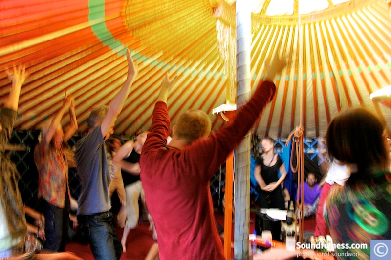 Group dancing with arms raised inside a colourful yurt