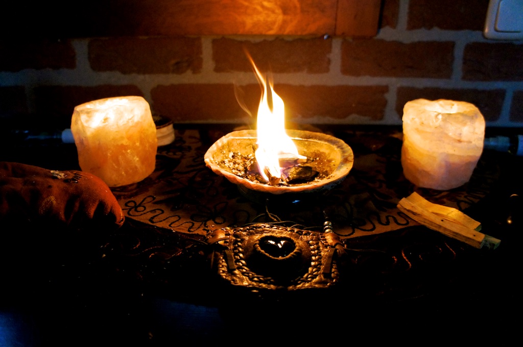 Abalone shell with burning herbs flanked by salt lamps on a ceremonial altar