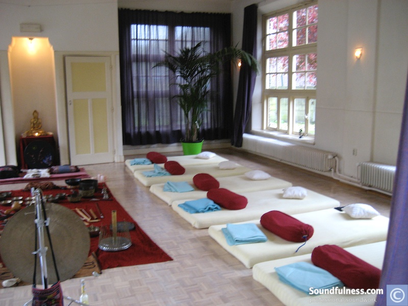 Row of floor mats with bolsters and blankets prepared for a sound session