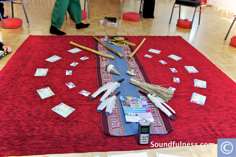 Central altar with feathers, flutes and Soundfulness cards laid on a red cloth