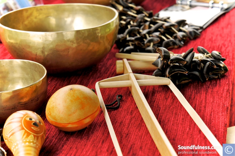 Close-up of a singing bowl, gourd shakers and a seed rattle on red cloth