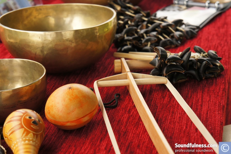 Singing bowls, seed shakers and wooden clappers arranged on a red cloth